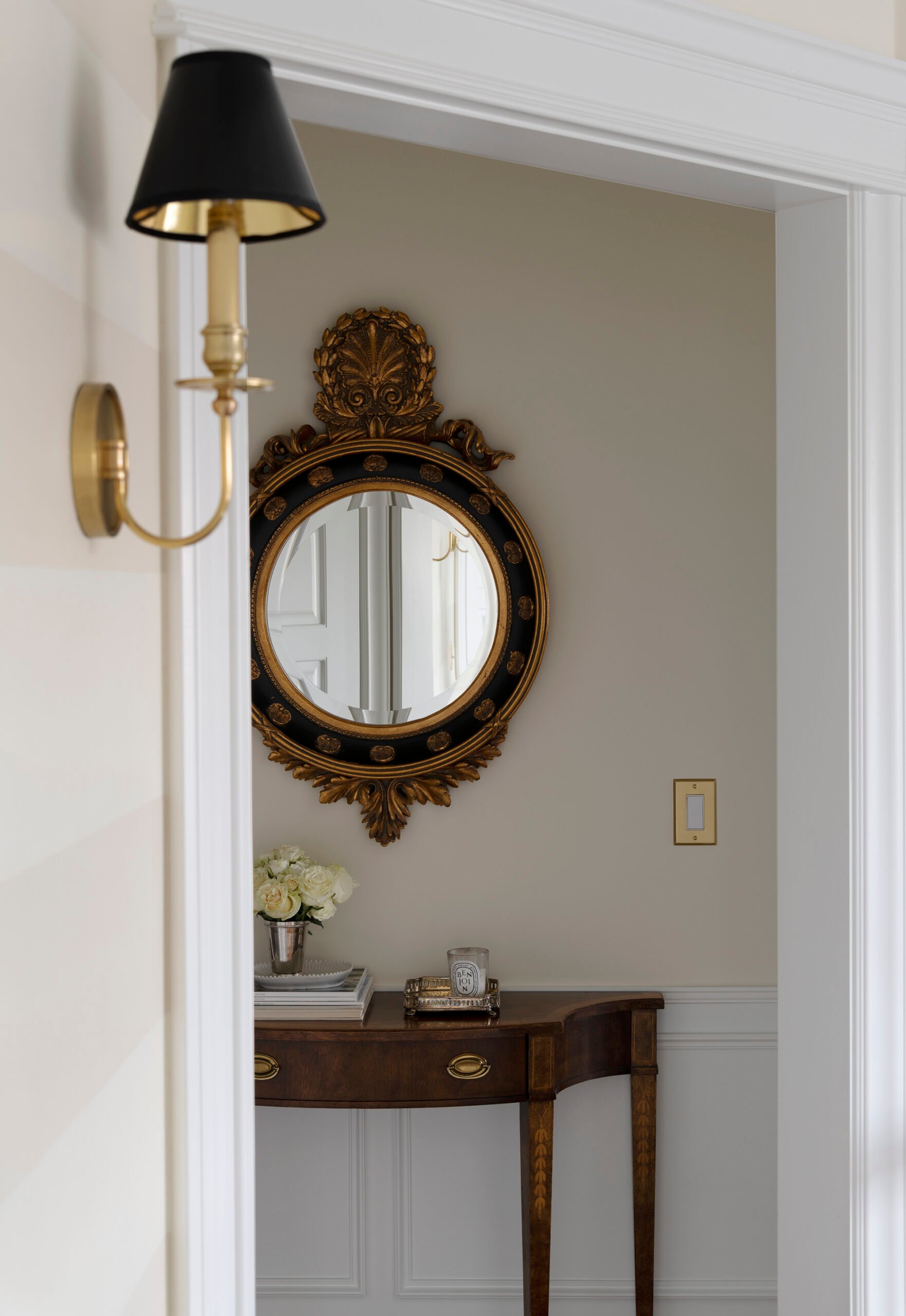 Antique gilded mirror in hallway above vintage demilune table