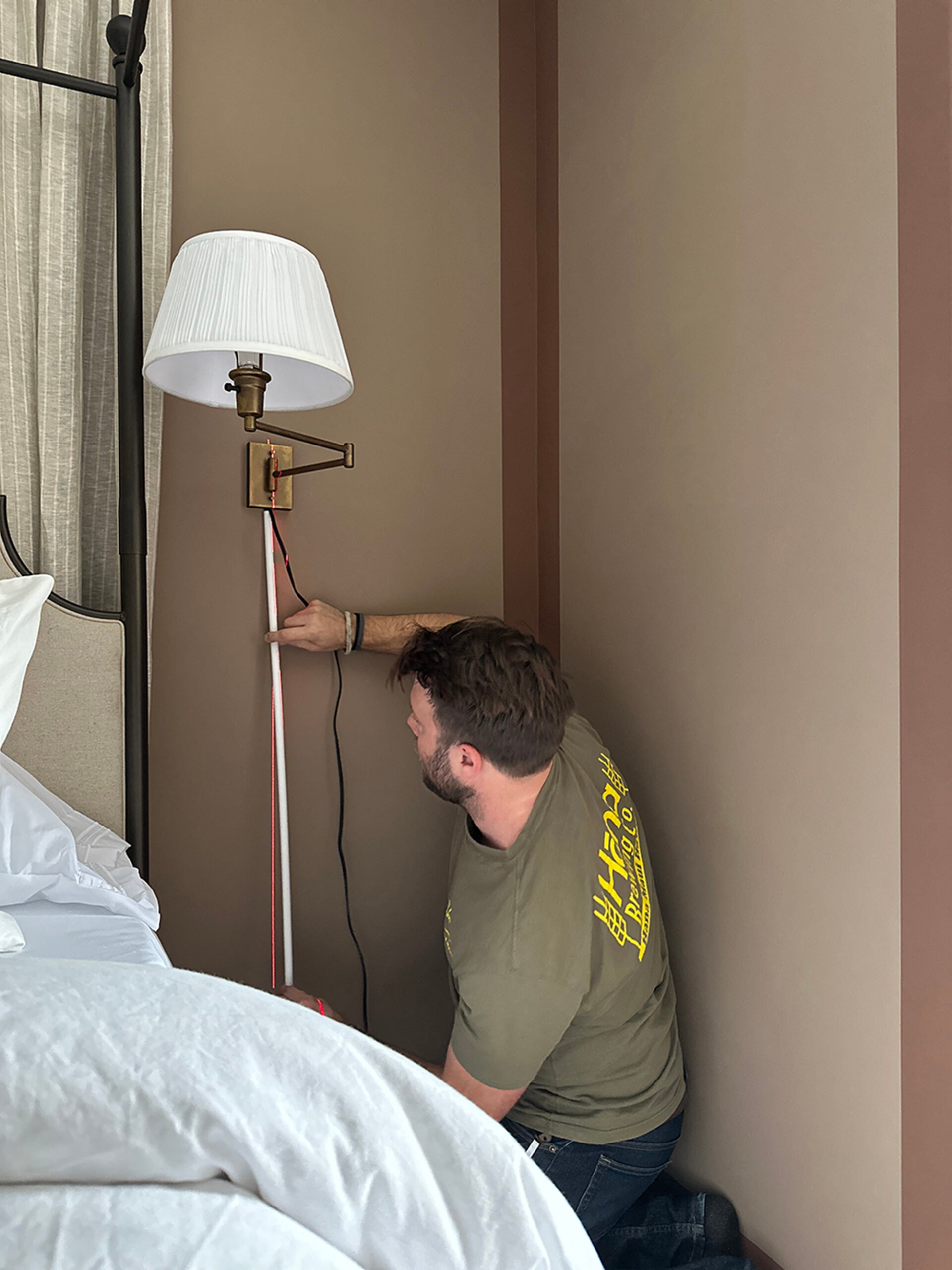 Adhering cord chase to the wall to hide and conceal an ugly sconce cord