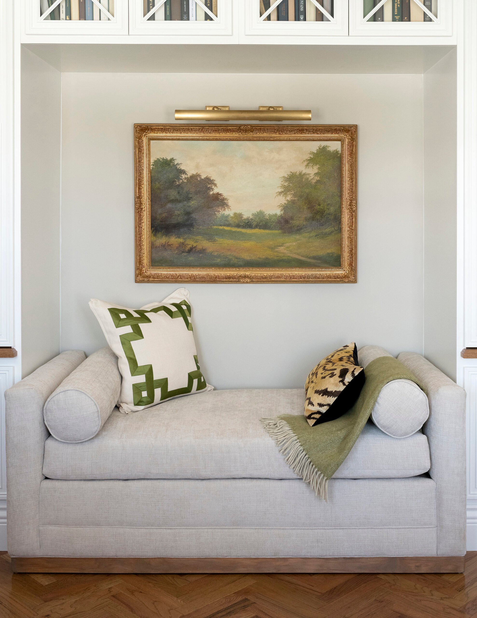 Daybed in between built-in bookcases with vintage art and bolster pillows