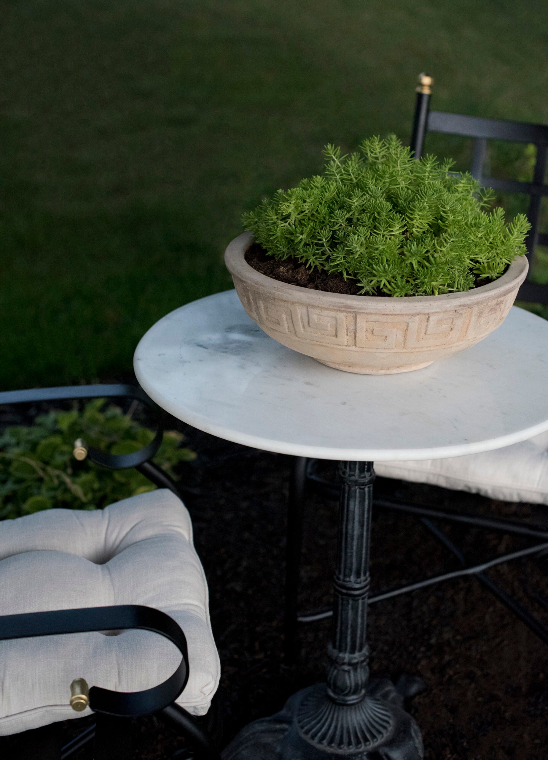 Greek key planter on marble table between iron bistro chairs