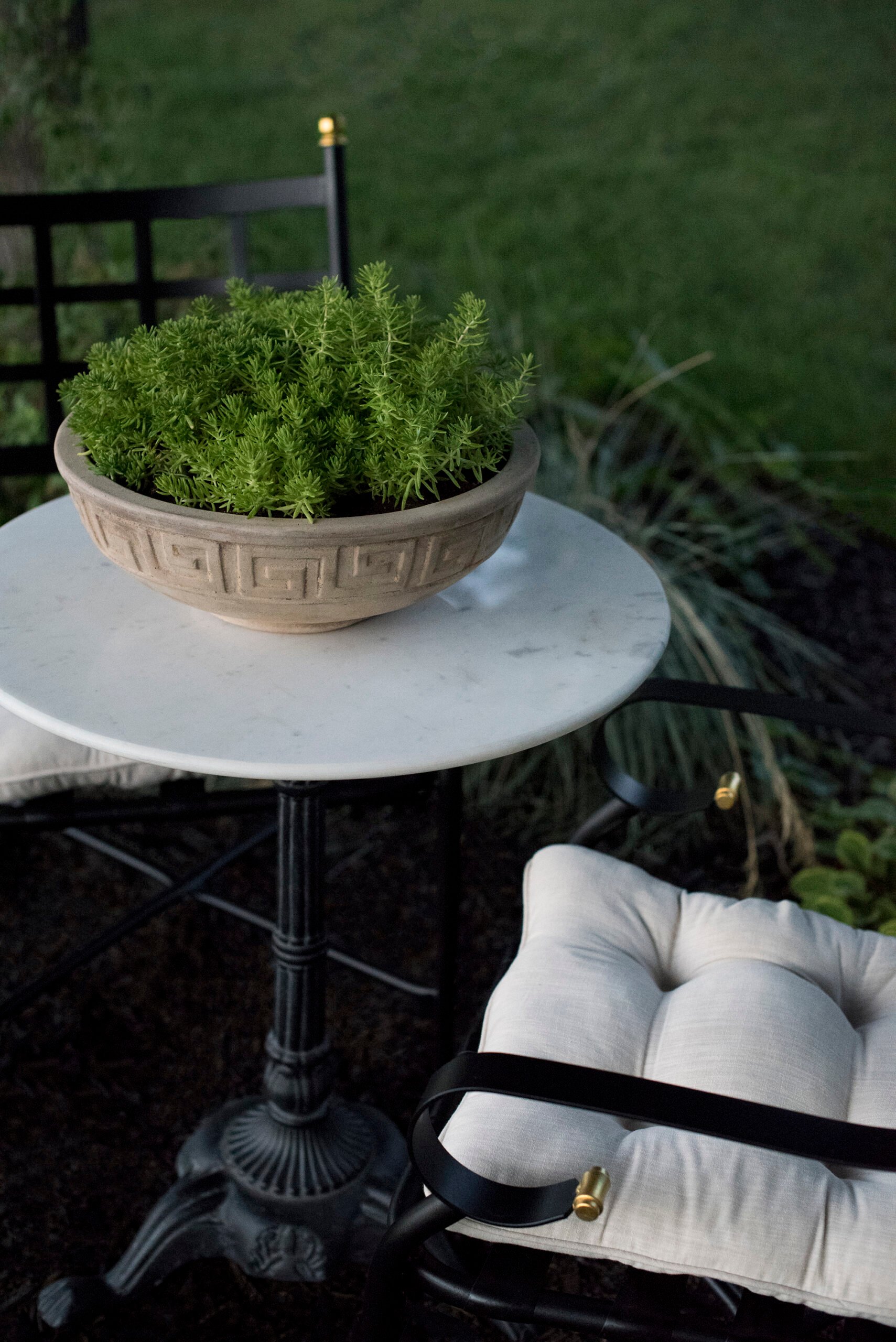 Greek key terracotta planter on marble table with iron bistro chairs