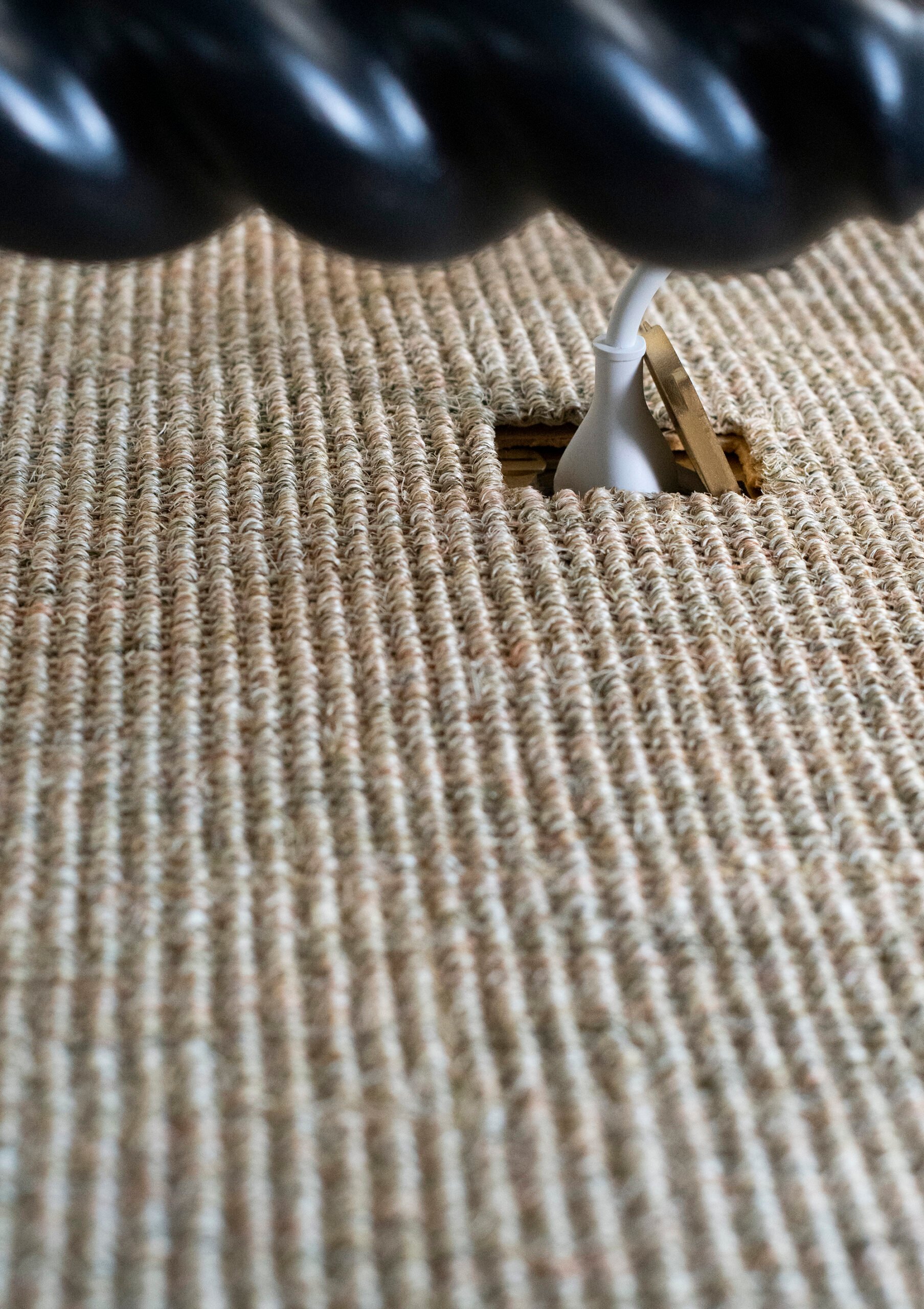 Hidden floor outlet beneath woven rug with computer plugged in for a clean solution