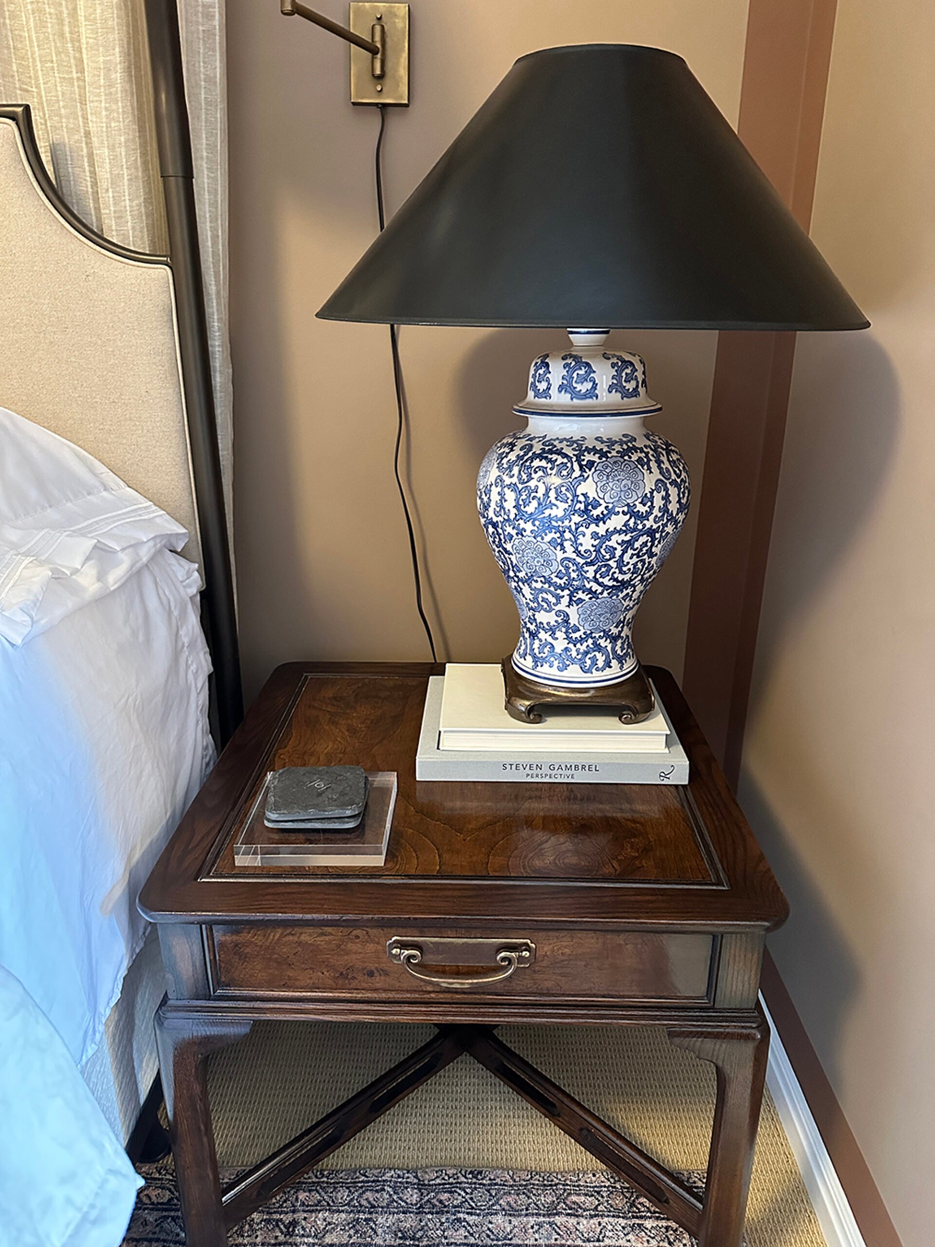Ugly black sconce cord dangling behind bedside nightstand, table lamp, and bedside vignette