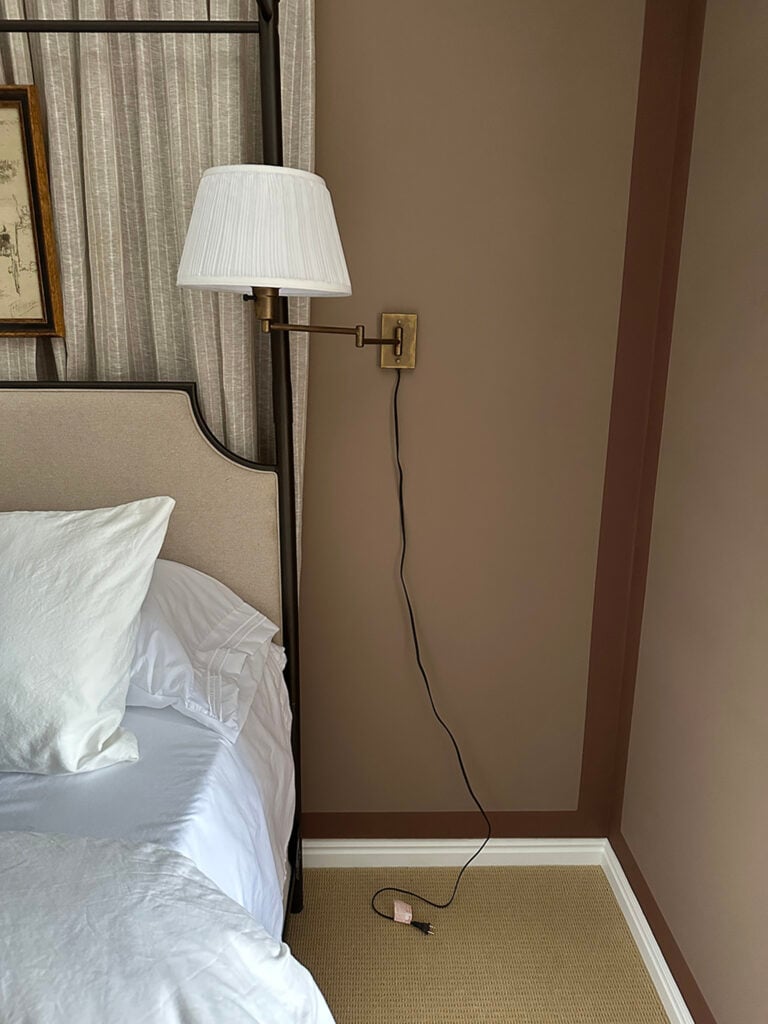 Ugly black sconce cord dangling beneath bedside sconce, unplugged