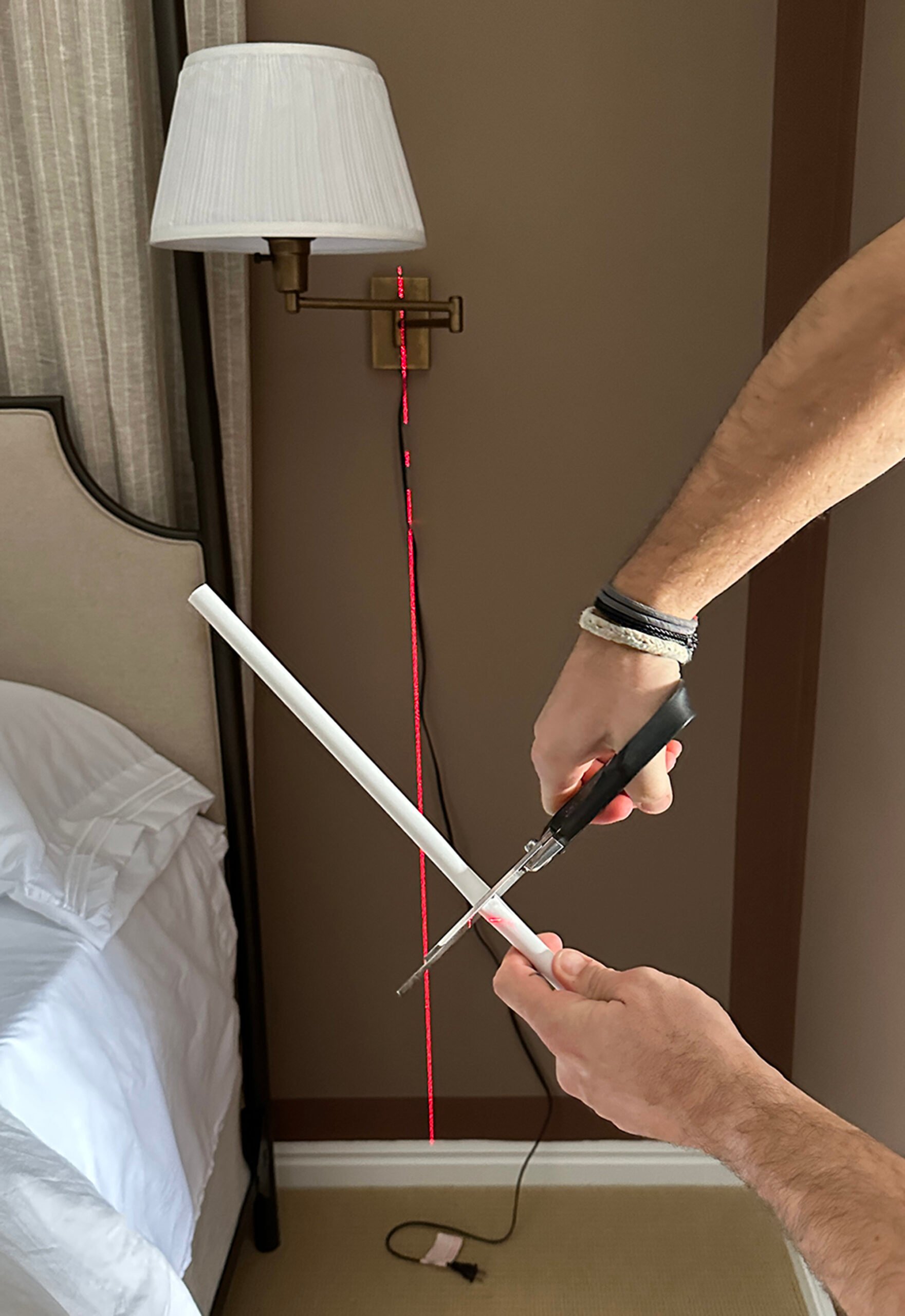 Cutting cord chase with regular scissors for concealing a bedroom sconce cord 