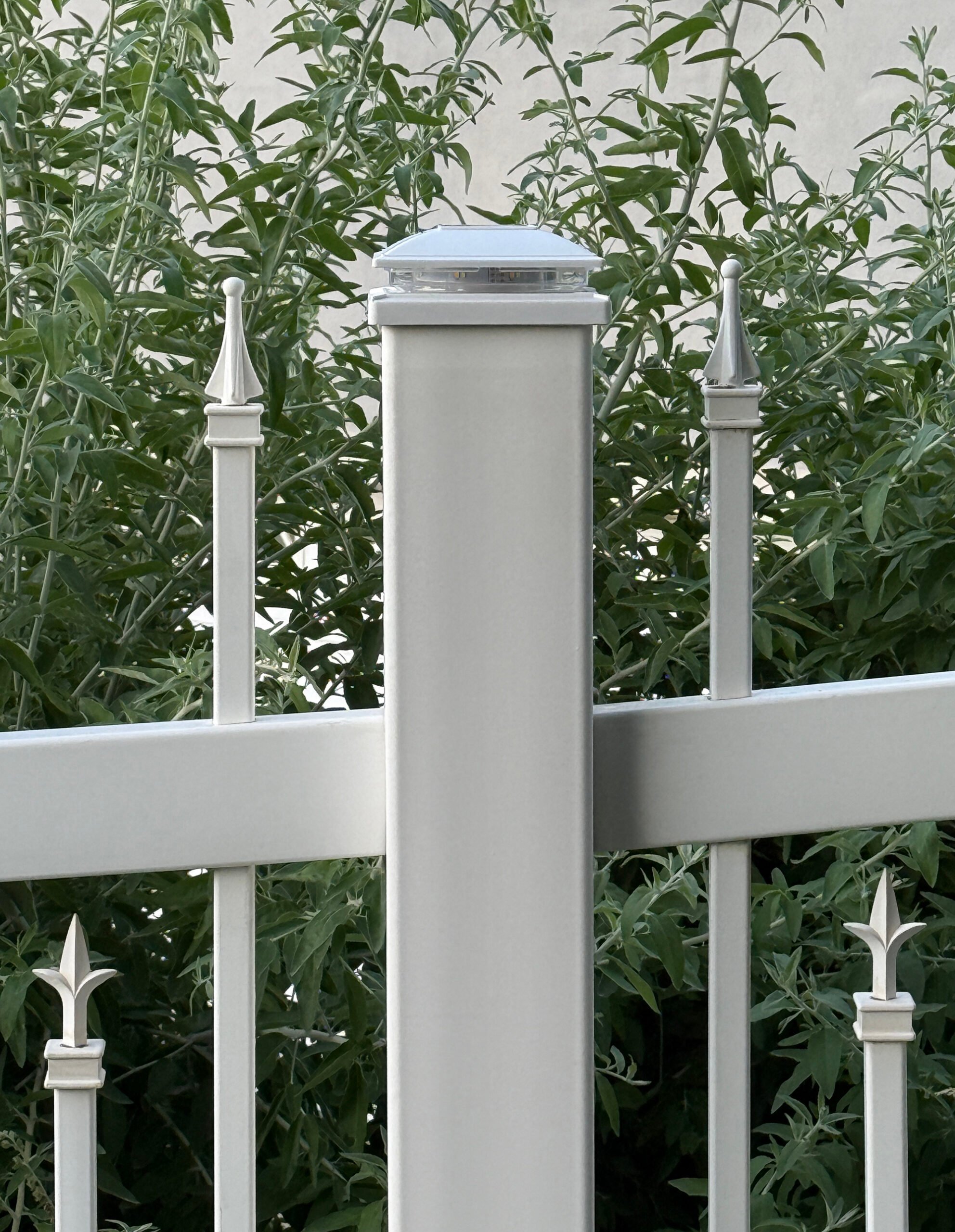 White vinyl fence with solar fence post cap light and traditional colonial finials for a traditional outdoor aesthetic