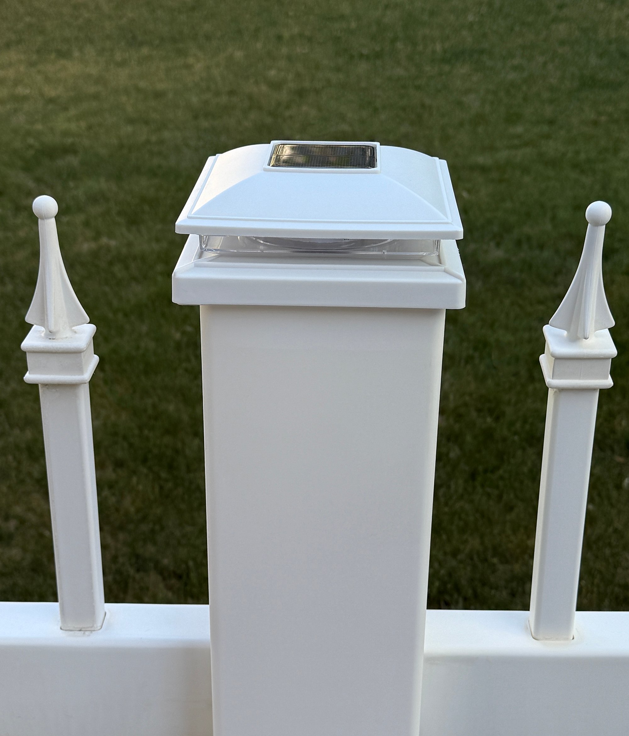 White vinyl fence with traditional finials and solar post cap light