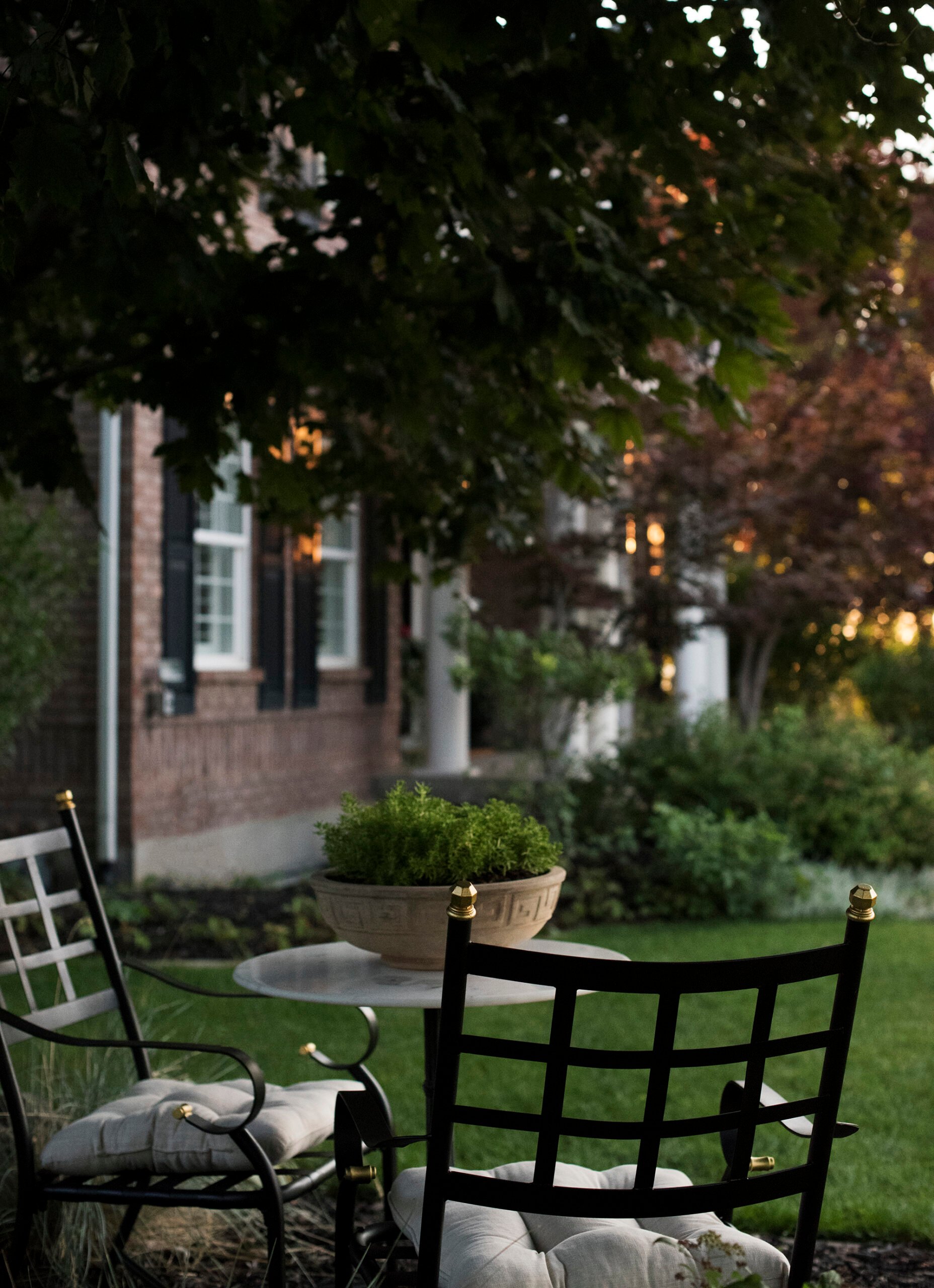 Iron patio chairs in side yard of brick colonial home