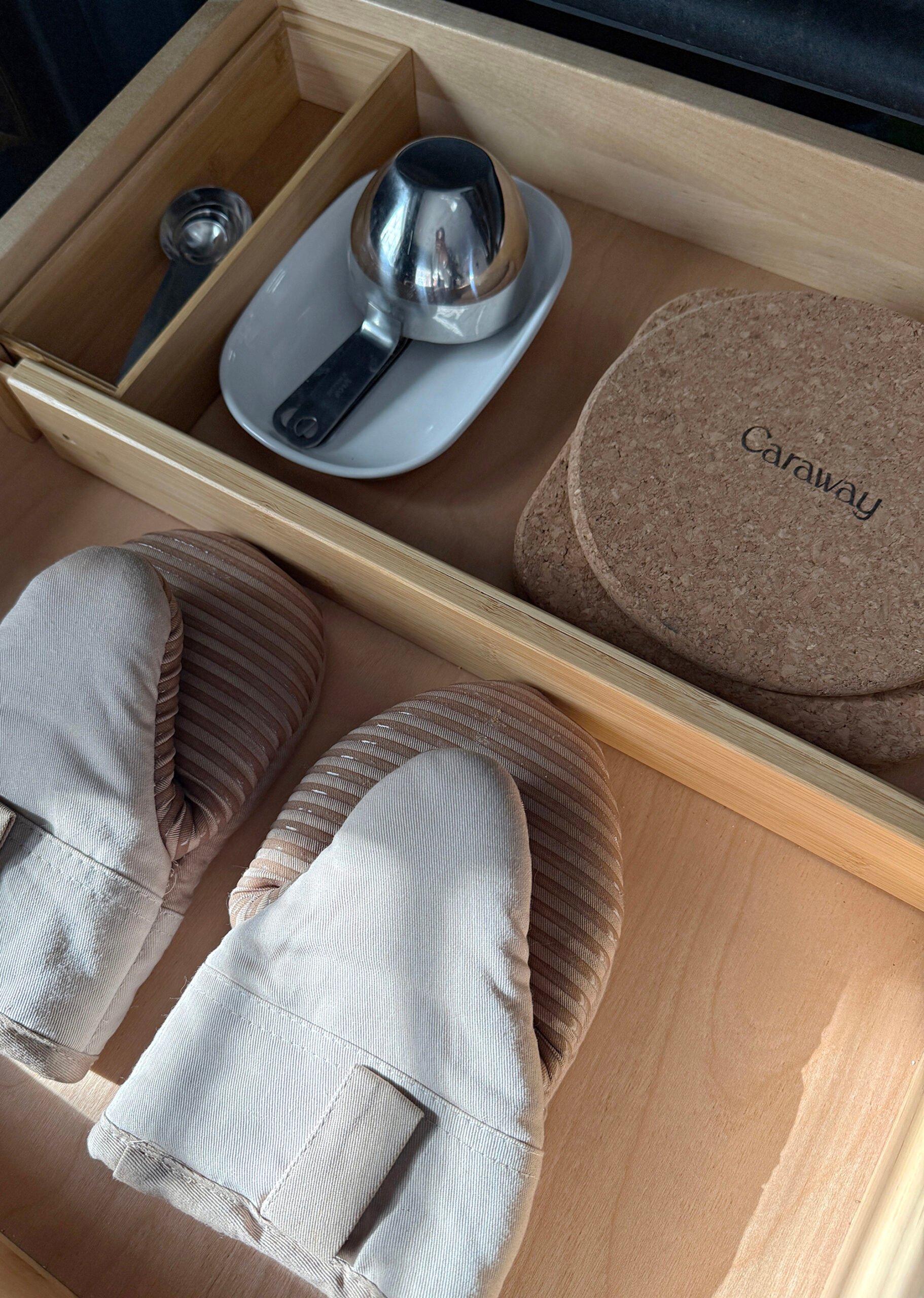 Organized kitchen drawers with measuring cups, oven mitts, and measuring spoons