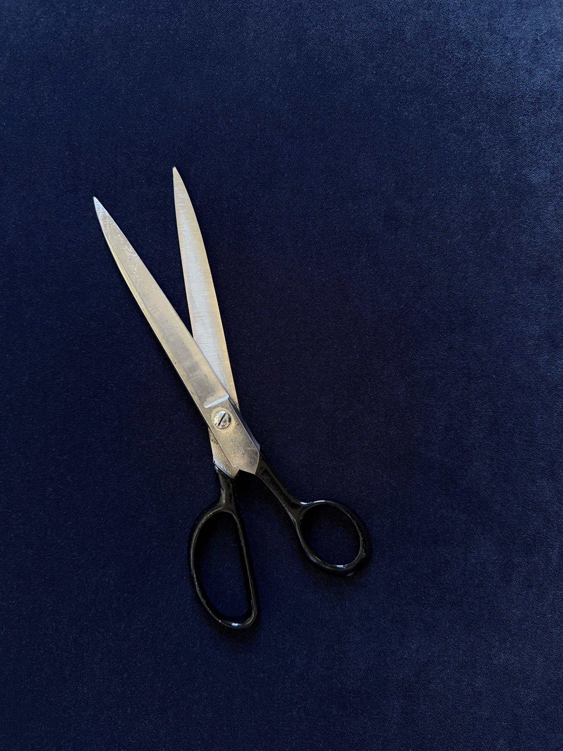 Scissors against velvet navy blue fabric