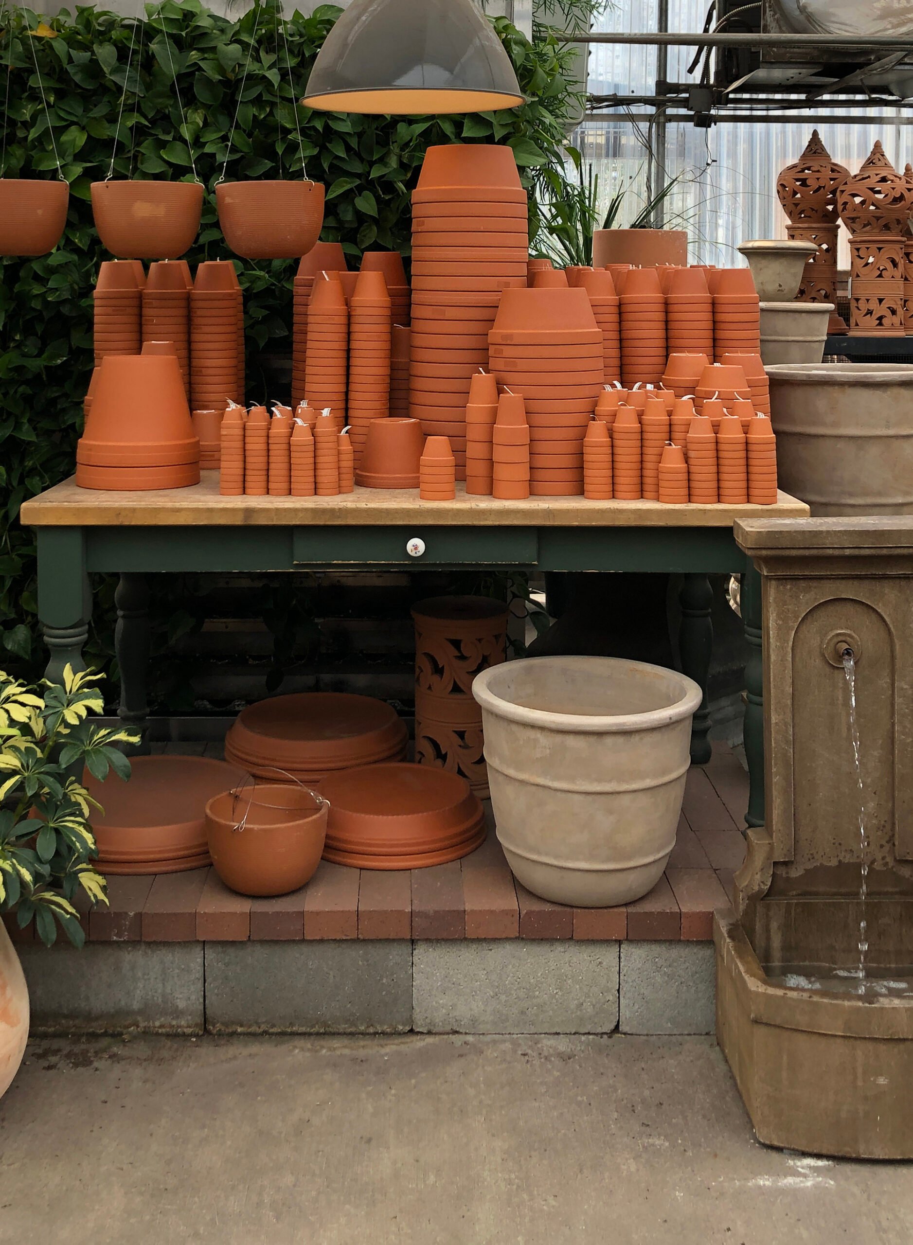 Stacks of terracotta planters in greenhouse on table