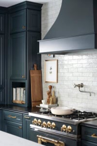 Kitchen with navy cabinets and a gas range with a gray tiled backsplash and Caraway cookware