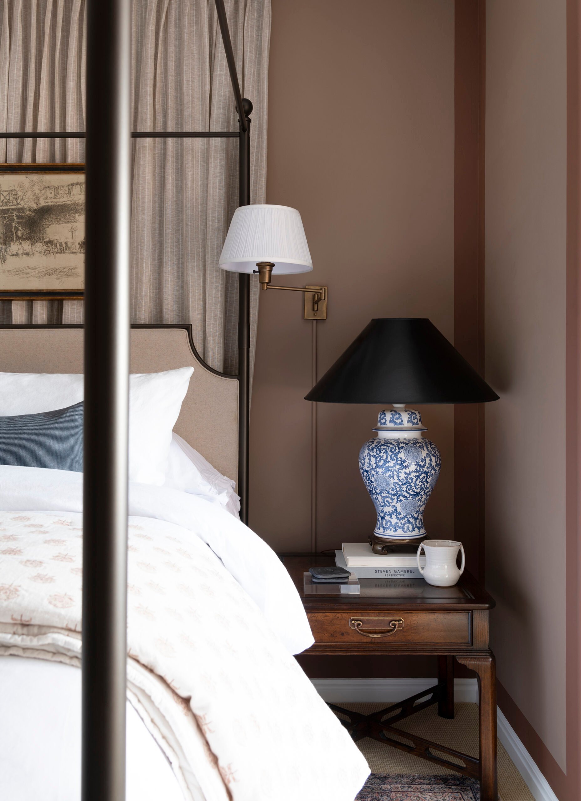 Vintage nightstand next to canopy bed with vintage blue and white lamp
